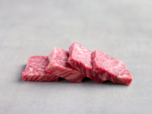 Four marbled wagyu slices overlapping in a row, seen from the side