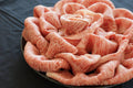 Thin marbled wagyu slices ruffled into a rose-like mound on a dark plate